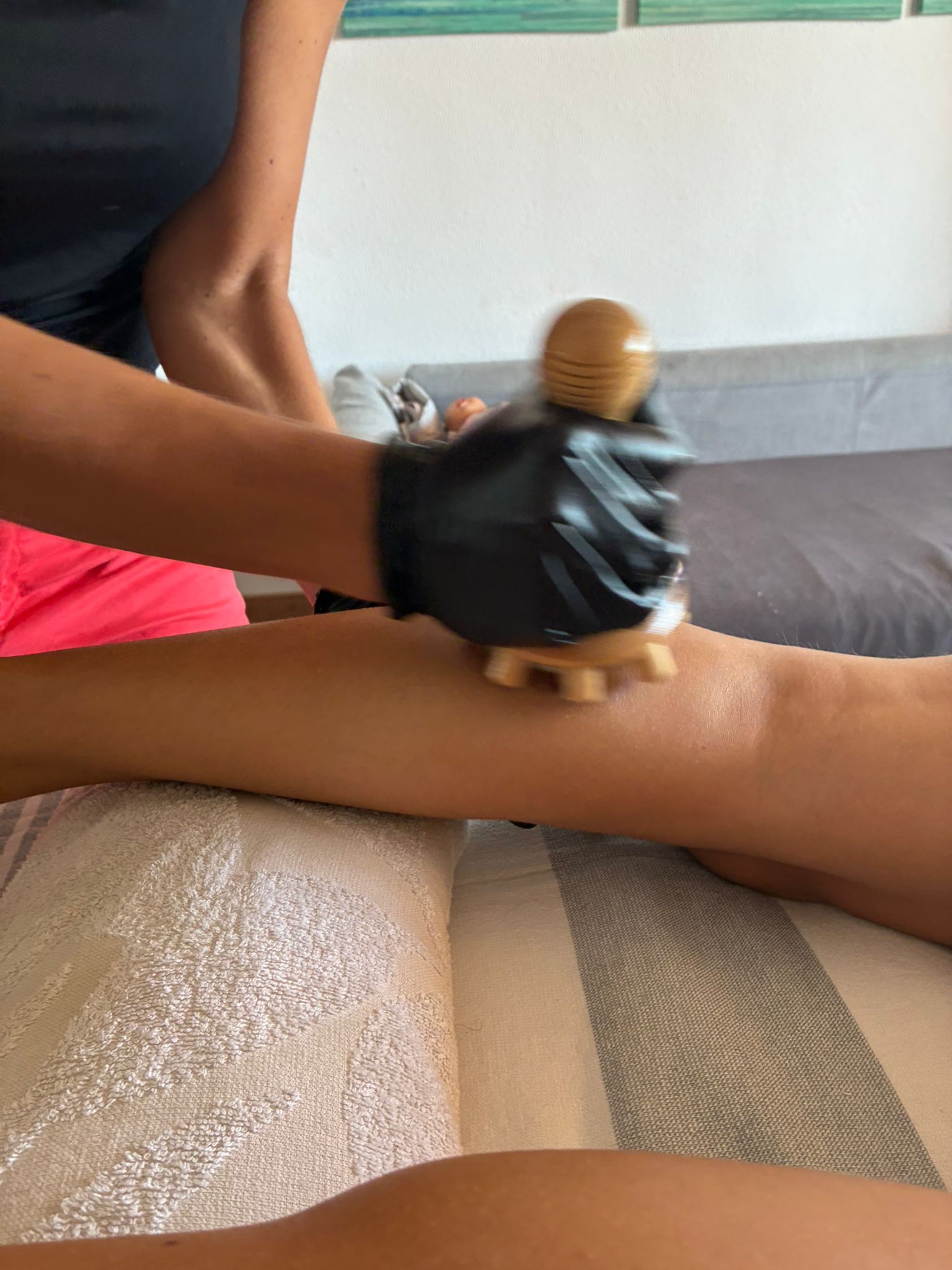 Herramienta de madera en forma de seta trabajando sobre la pantorrilla de una clienta