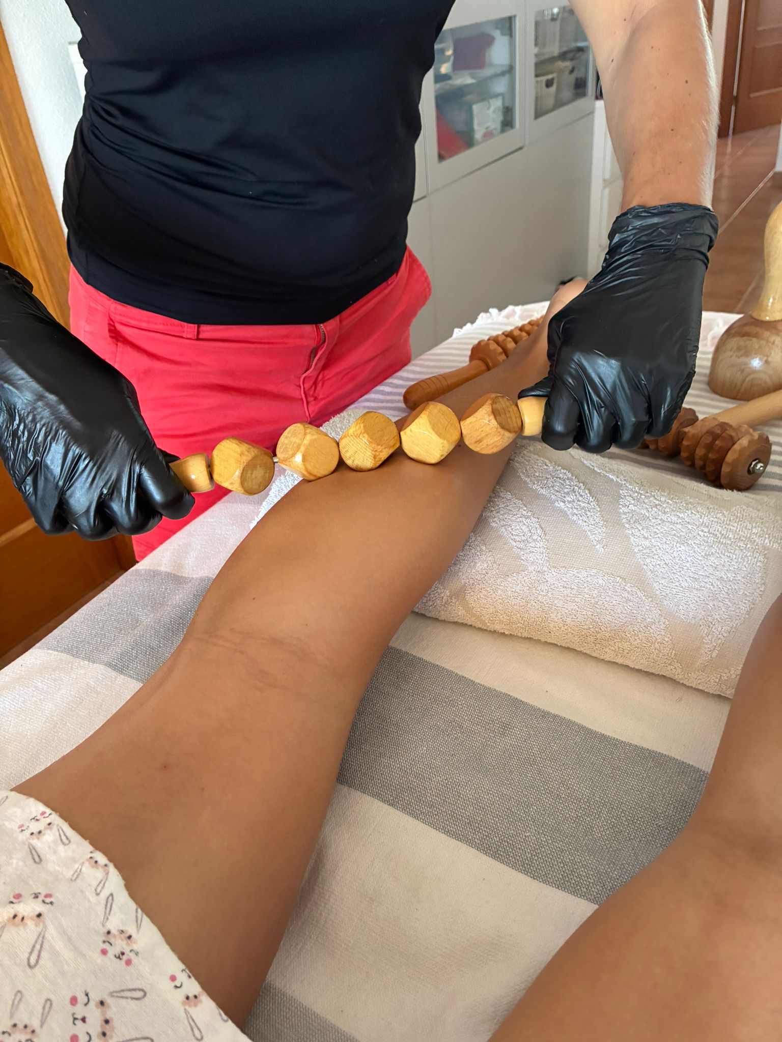 Primer plano de un rodillo de madera deslizándose por una pierna con aceite durante la sesión